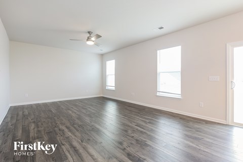 A spacious room with wooden flooring and a ceiling fan.