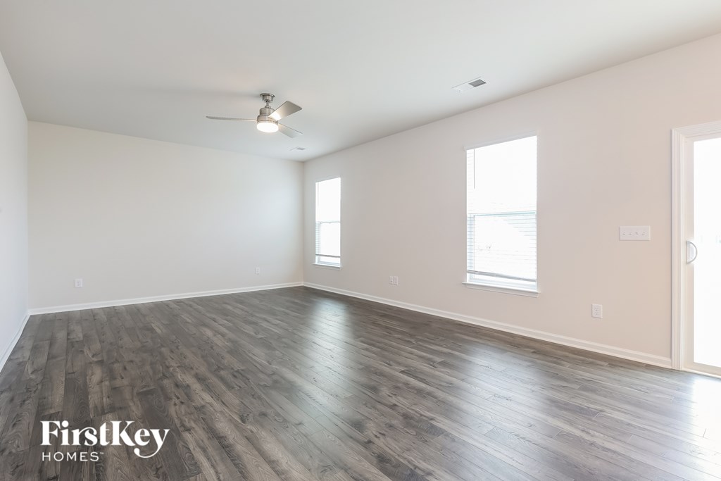 A spacious room with wooden flooring and a ceiling fan.