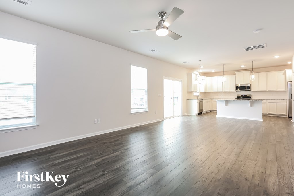 A spacious room with wooden floors and a kitchen area in the background.