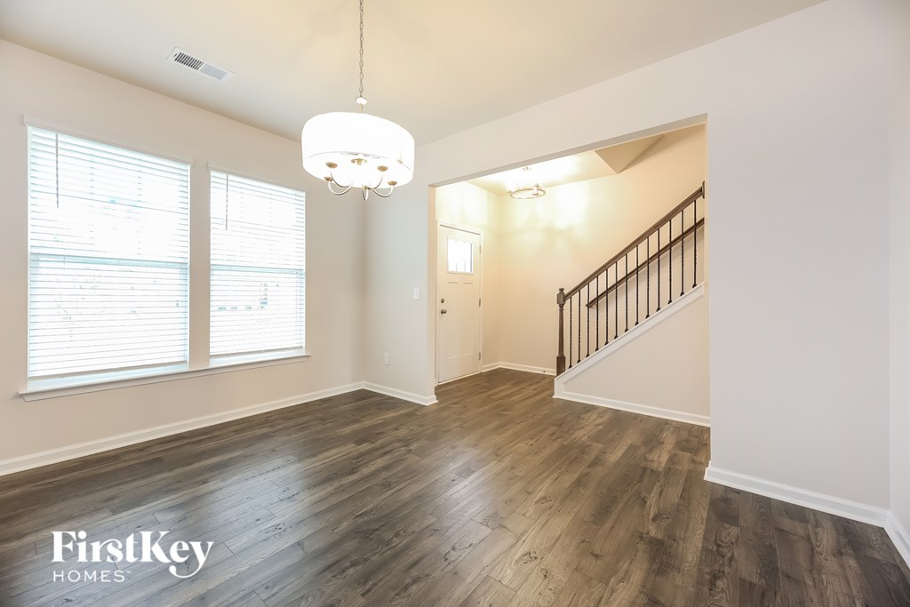 A spacious room with wooden floors and a staircase.