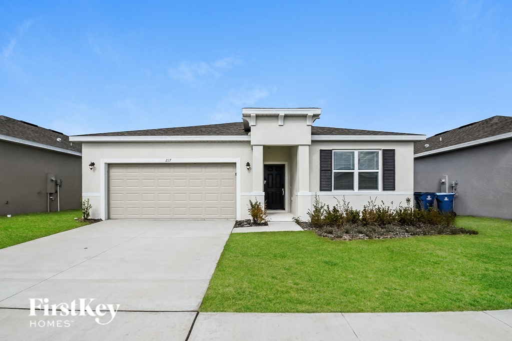 a white house with a garage door and a lawn