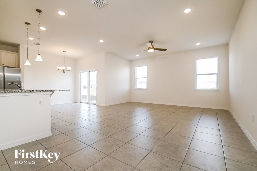 an empty kitchen and living room with white walls and tile floors
