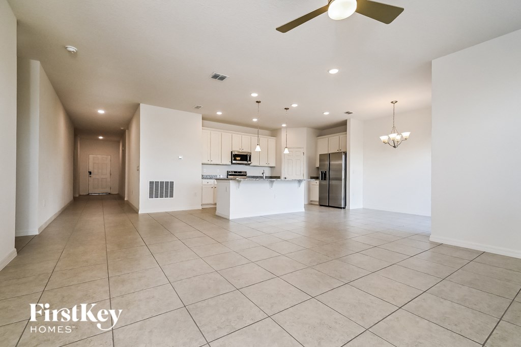 an open kitchen and living room with white walls and tile flooring
