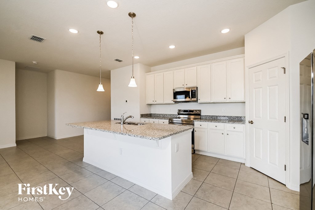 a large kitchen with white cabinets and granite counter tops