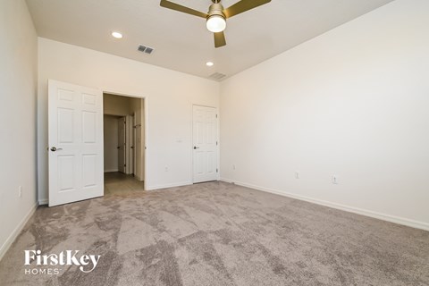 a spacious living room with carpet and a ceiling fan