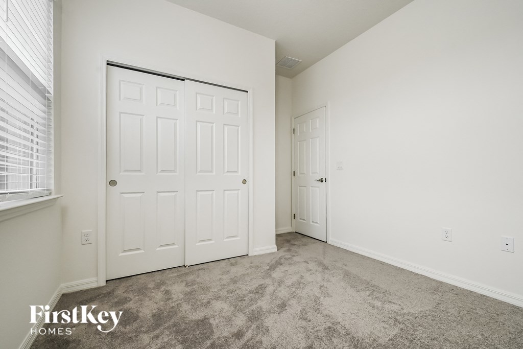 a bedroom with white doors and carpet and a door to a closet