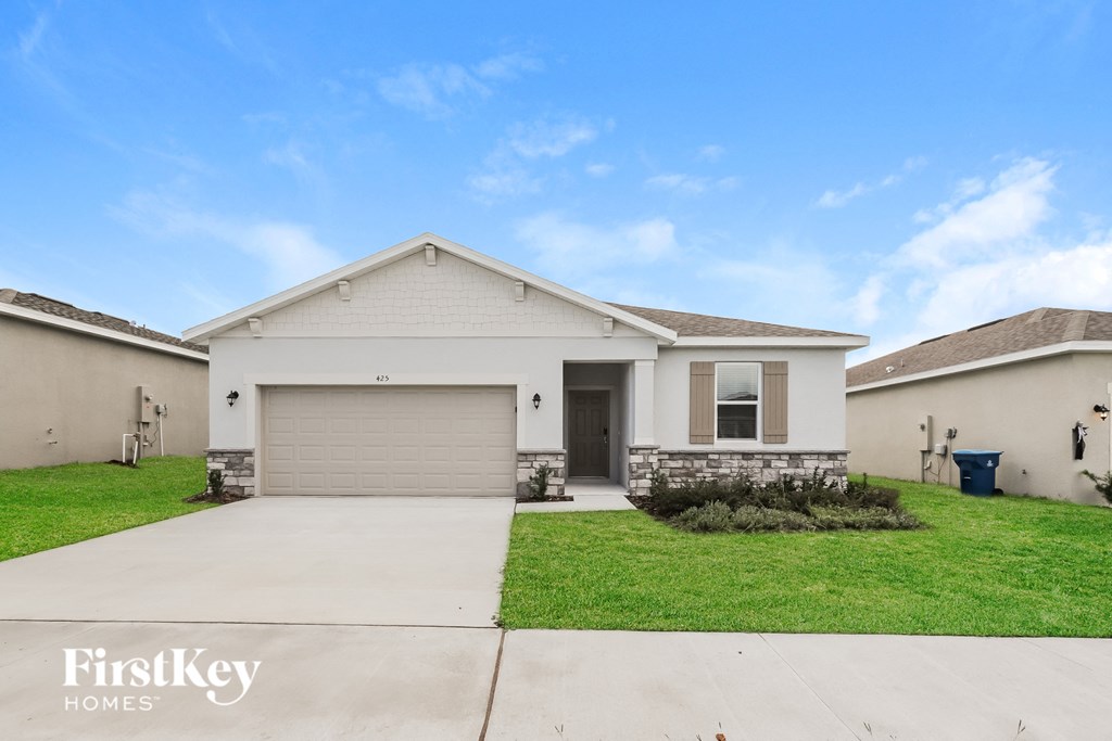 a beige house with a garage door and a lawn