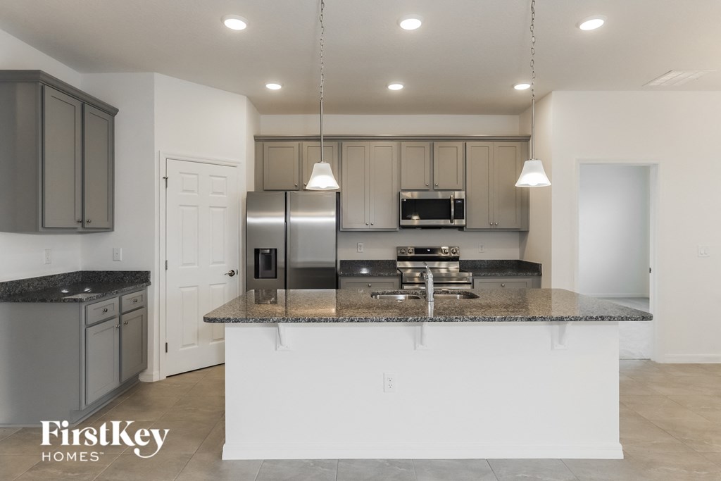 a white kitchen with granite counter tops and stainless steel appliances