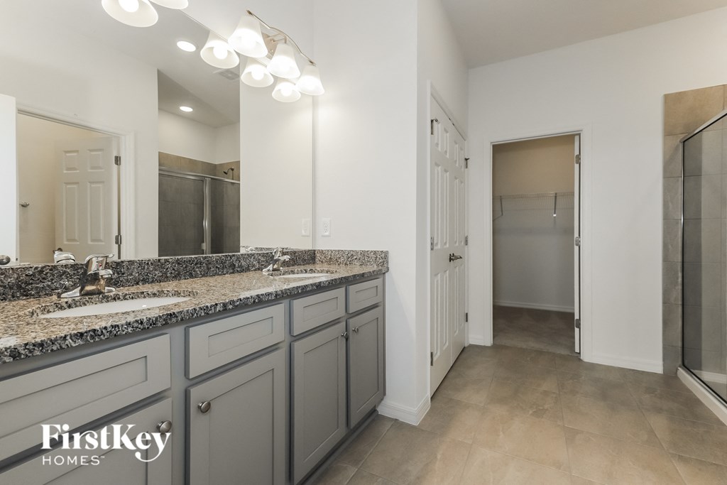 the master bathroom has dual sinks and a large mirror