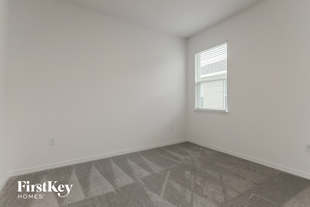 the living room of a home with white walls and a window