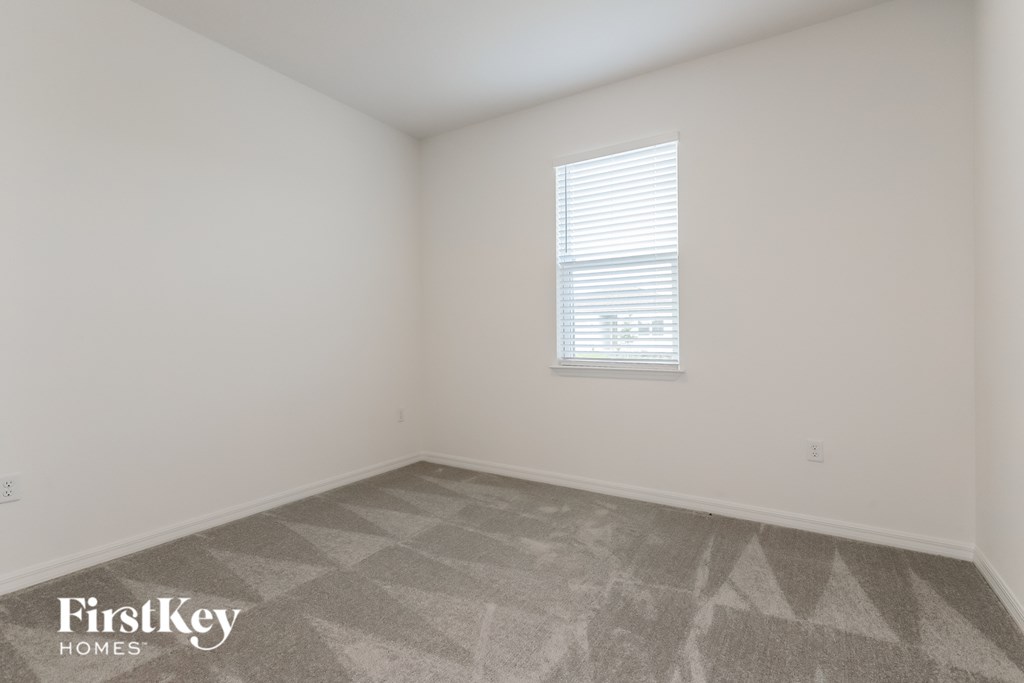 the living room of a home with white walls and a window