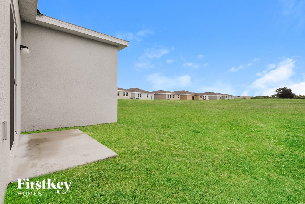 the backyard of a house with a green lawn and some apartments in the background