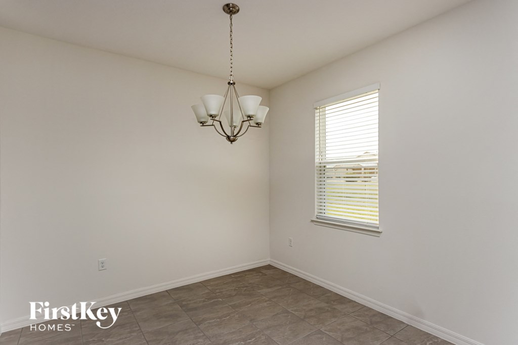A room with a chandelier and a window with blinds.