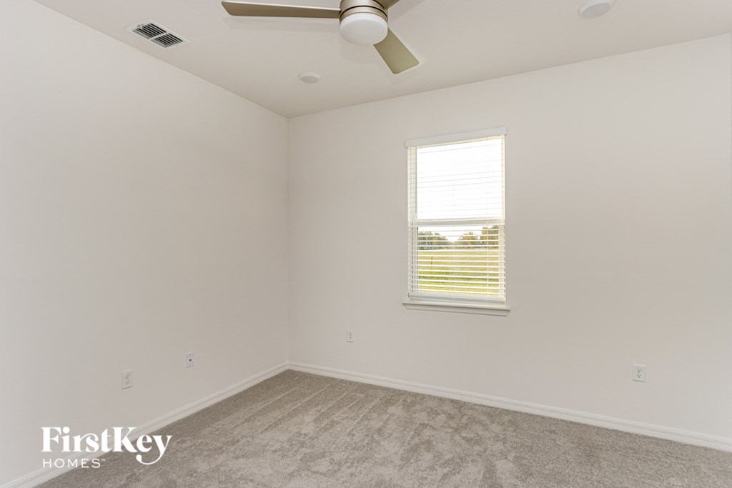 A room with a ceiling fan and a window with blinds.