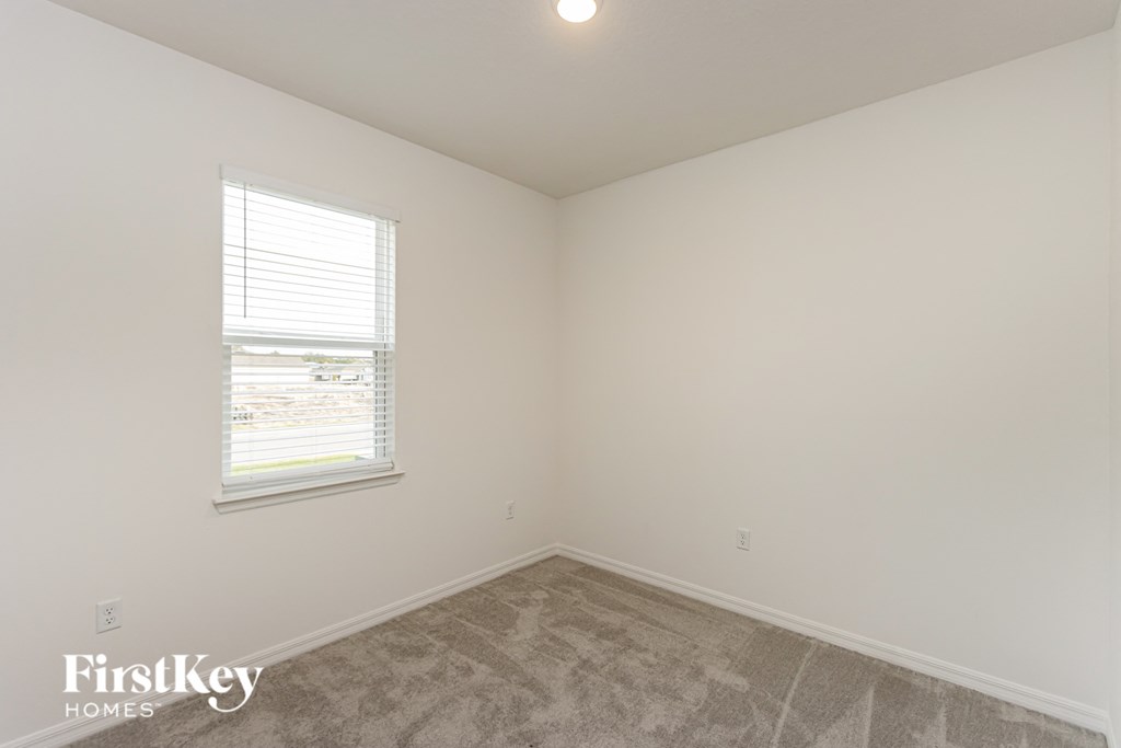 A room with a window and a carpeted floor.