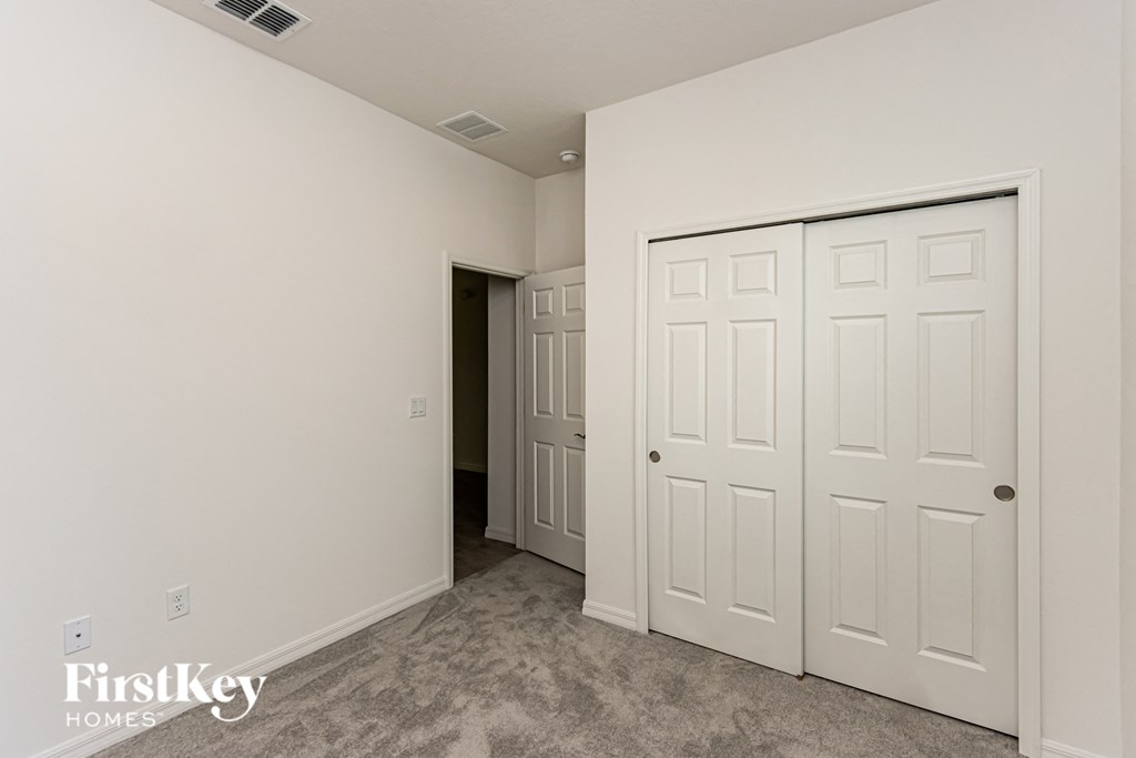 A room with a white door and a carpeted floor.