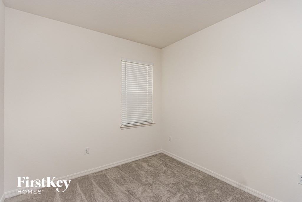 A room with a carpeted floor and a window with blinds.