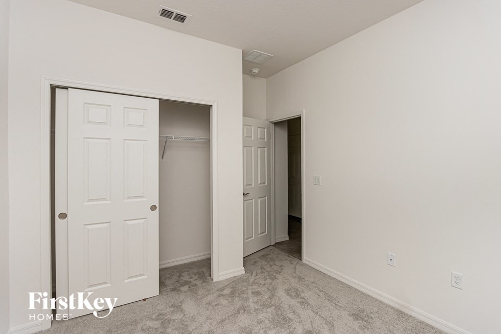 A white door is open to a room with a carpeted floor.