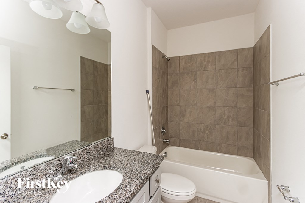 A bathroom with a white tub, sink, and toilet.