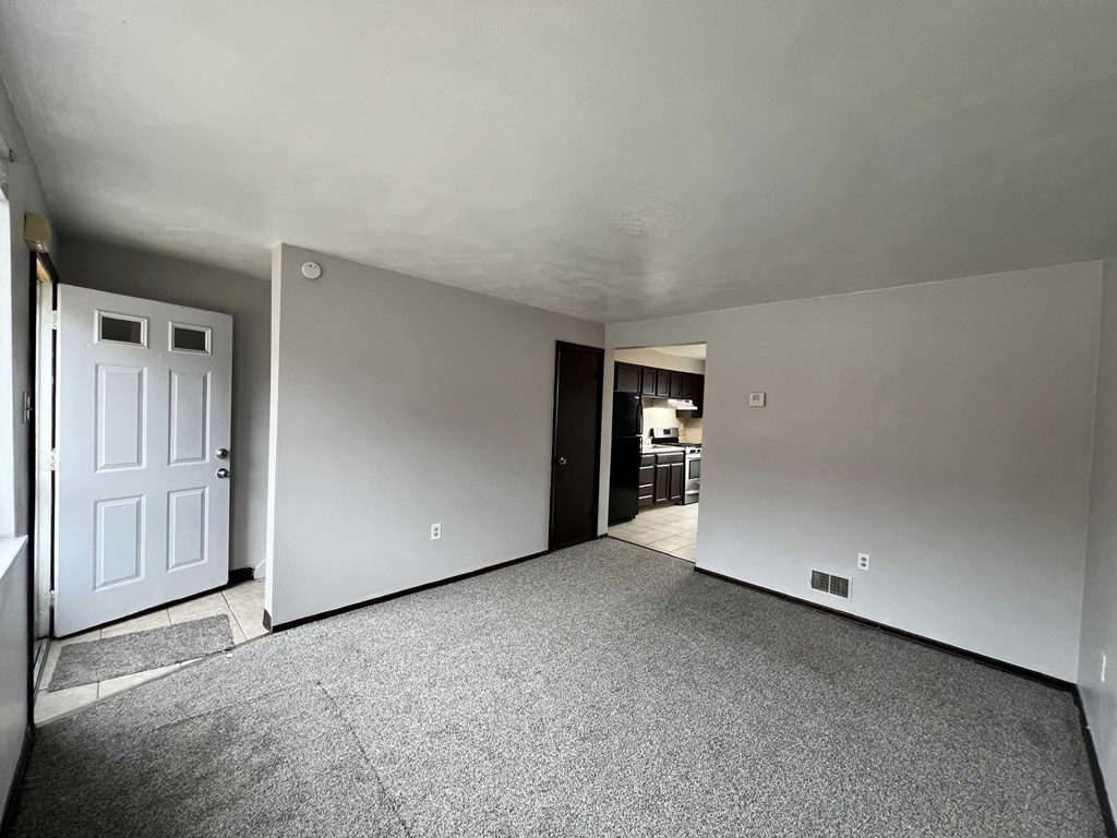 A room with a carpeted floor and a white door.
