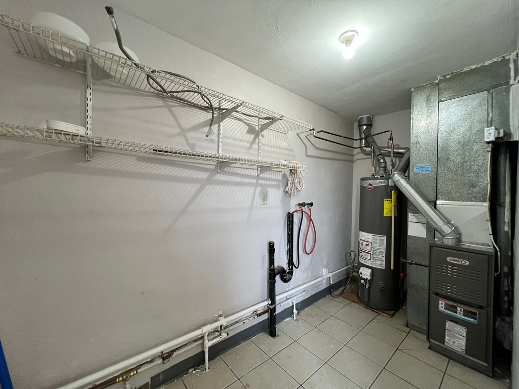 A utility room with a furnace and pipes.