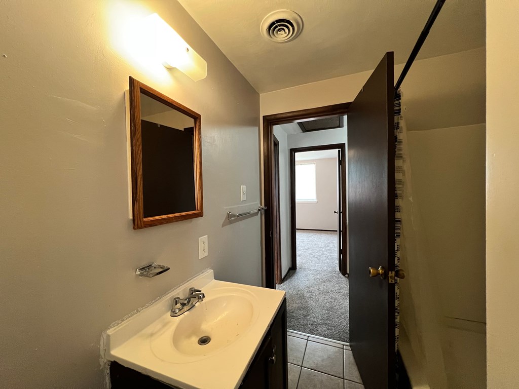 A bathroom with a sink, mirror, and door.