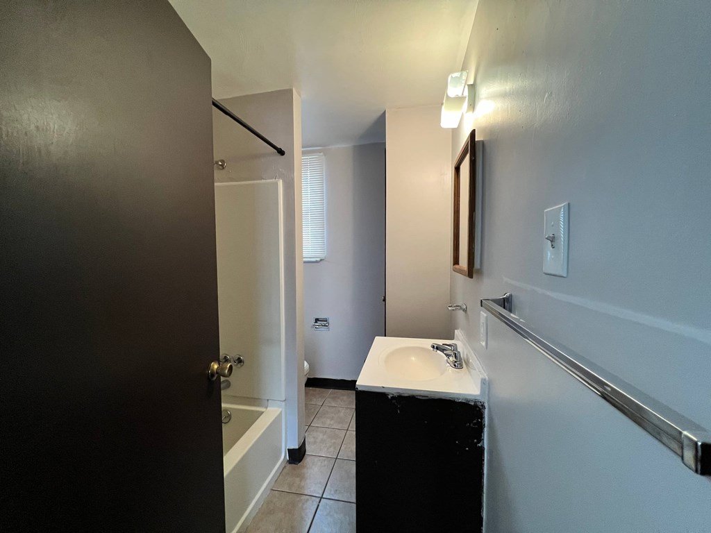 A bathroom with a sink, mirror, and toiletries.