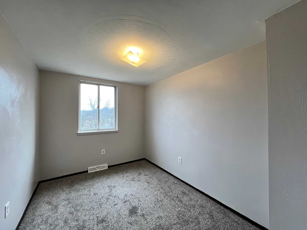 A room with a window and carpeted floor.