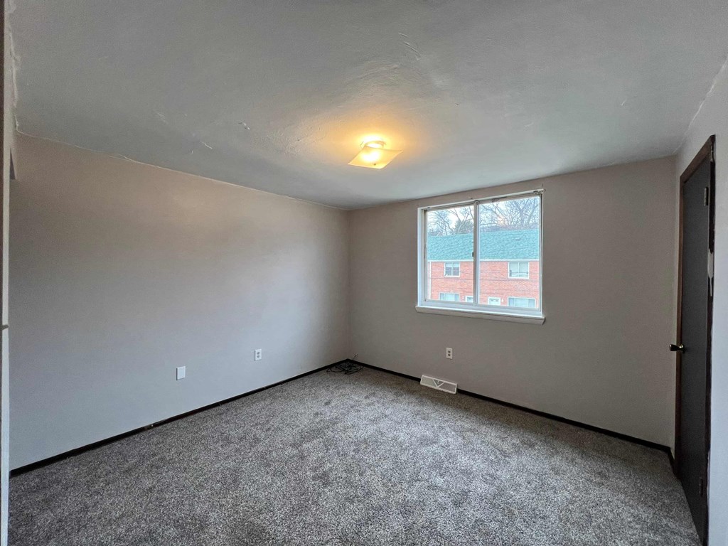 A room with a window showing a red building outside.