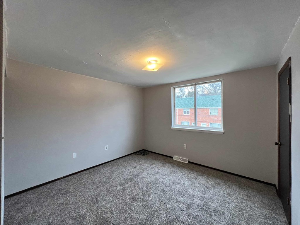 A room with a window showing a red building outside.