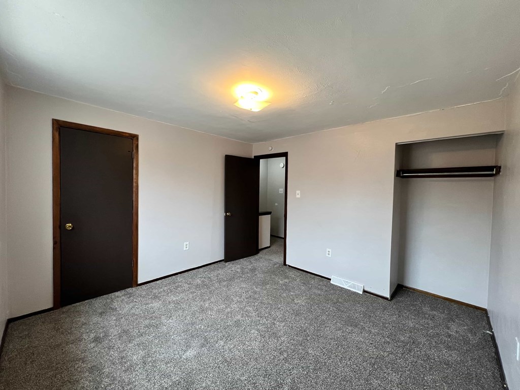 A room with a carpeted floor and a door on the left side.
