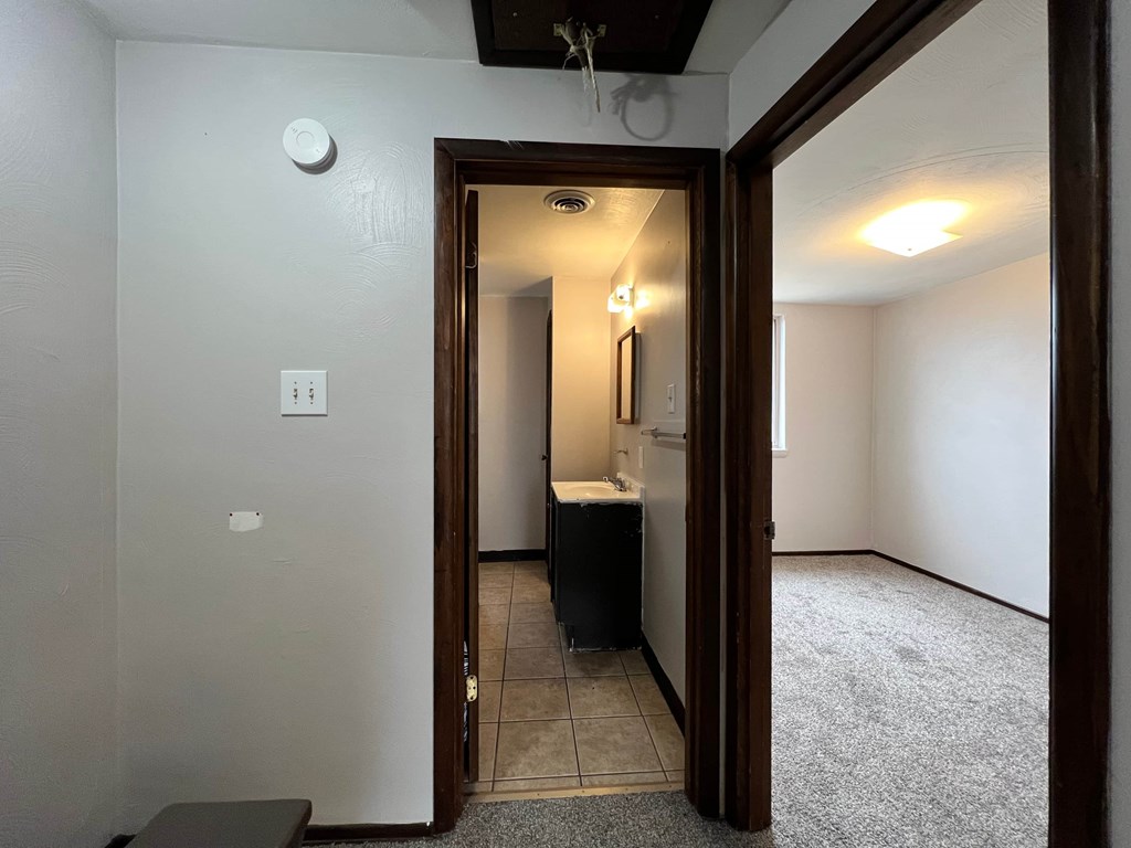 A bathroom with a white wall and a white toilet.