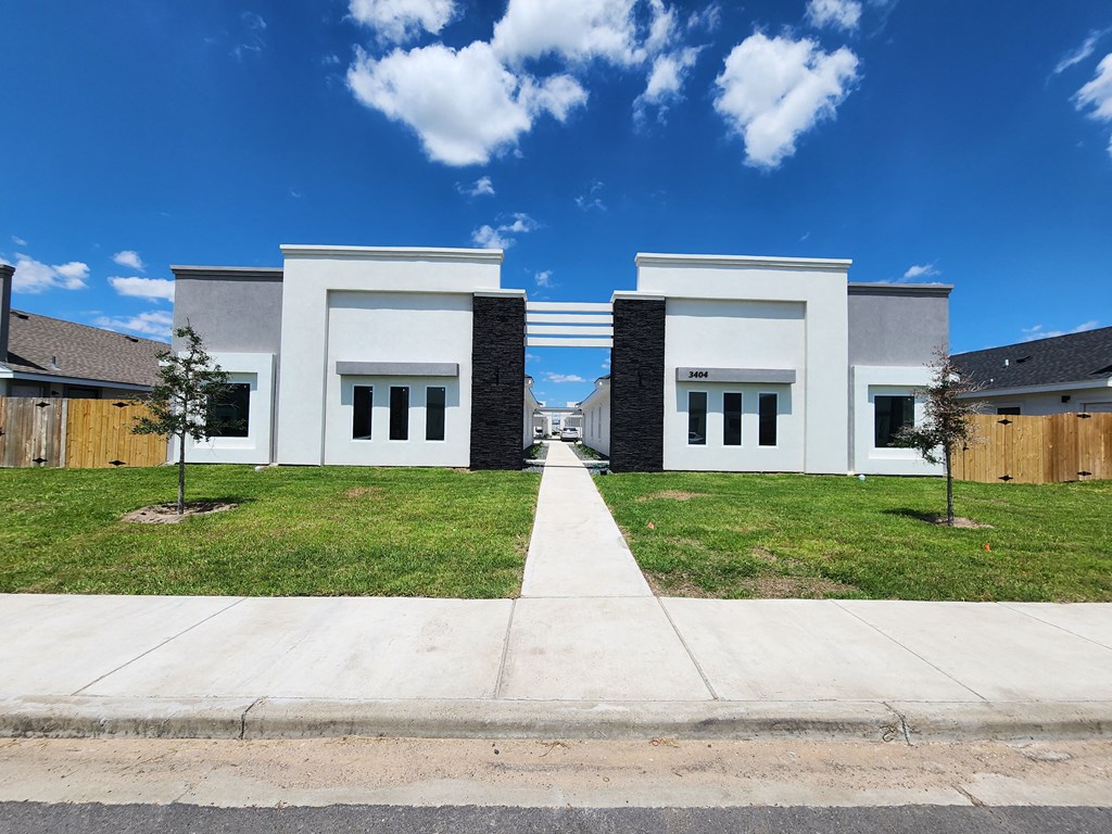 the front of a white house with grass and a sidewalk