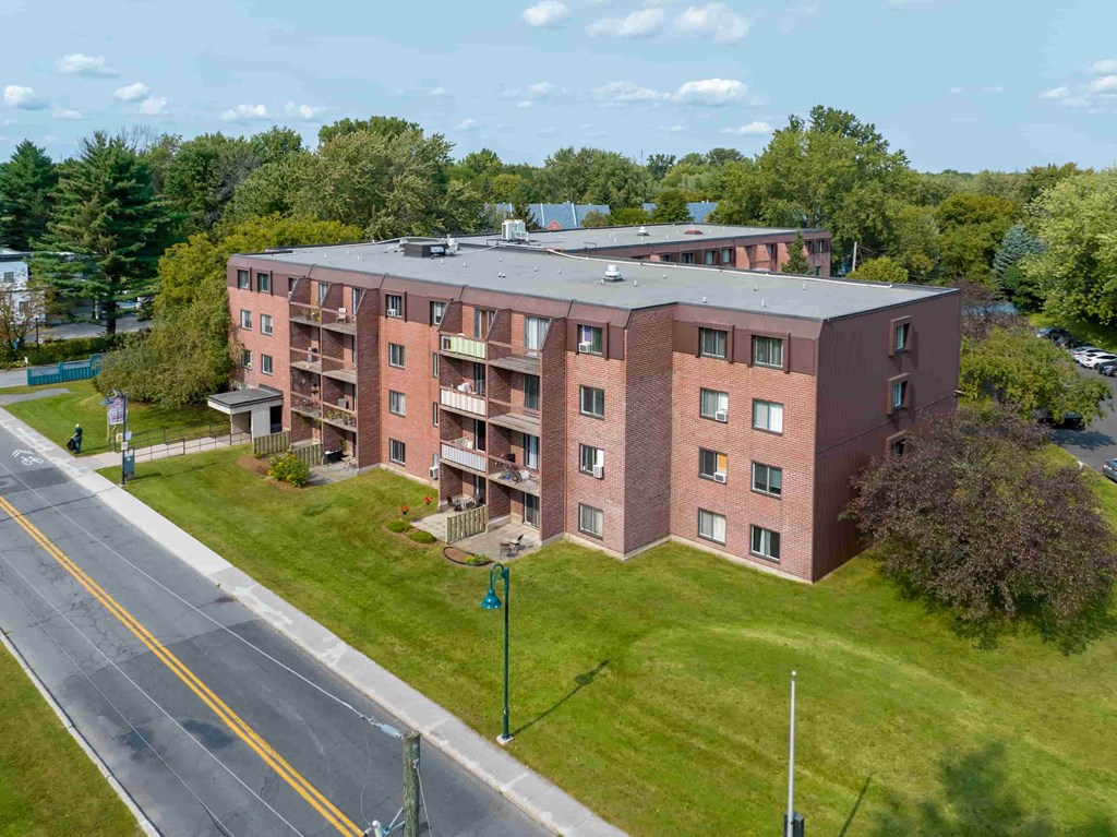 an aerial view of a brick apartment building on the side of a road