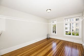 an empty living room with hardwood floors and two windows