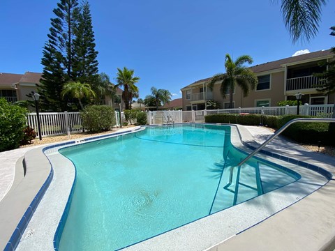 a swimming pool in front of a building with palm trees