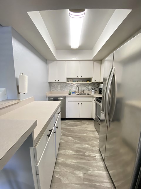 an empty kitchen with white cabinets and stainless steel appliances