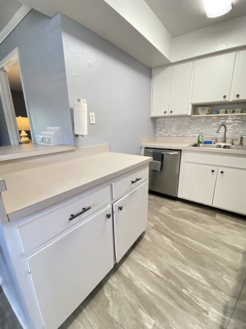 an empty kitchen with white cabinets and stainless steel appliances