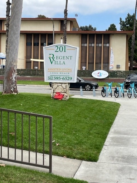 a sign in the grass in front of a building