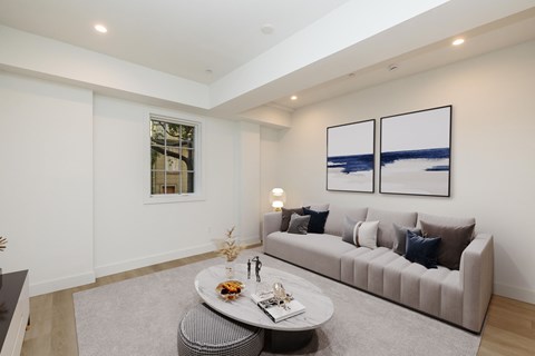 A living room with a grey couch, a coffee table, and two framed pictures on the wall.
