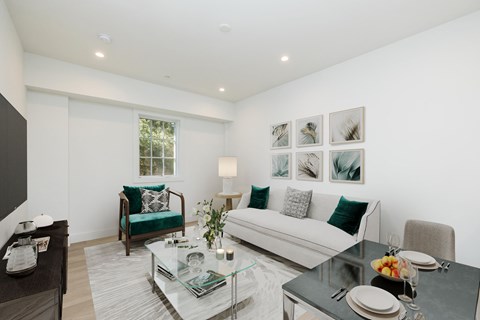 A modern living room with a glass coffee table and a white couch.