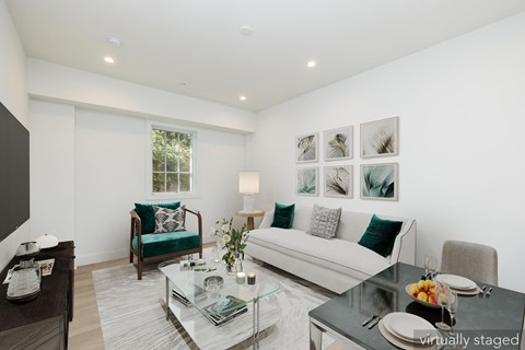 A modern living room with a glass coffee table and a white couch.