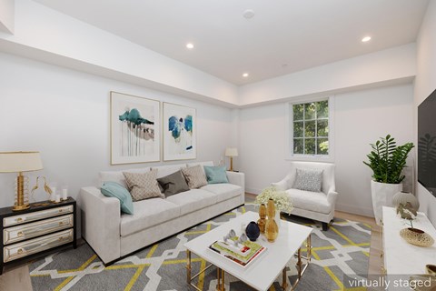 A living room with a white couch, a coffee table, and a painting on the wall.