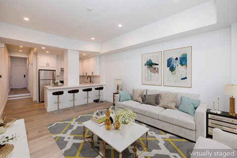A living room with a couch, coffee table, and bar stools.