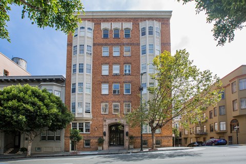 A tall building with a mix of red and white bricks stands between two trees.