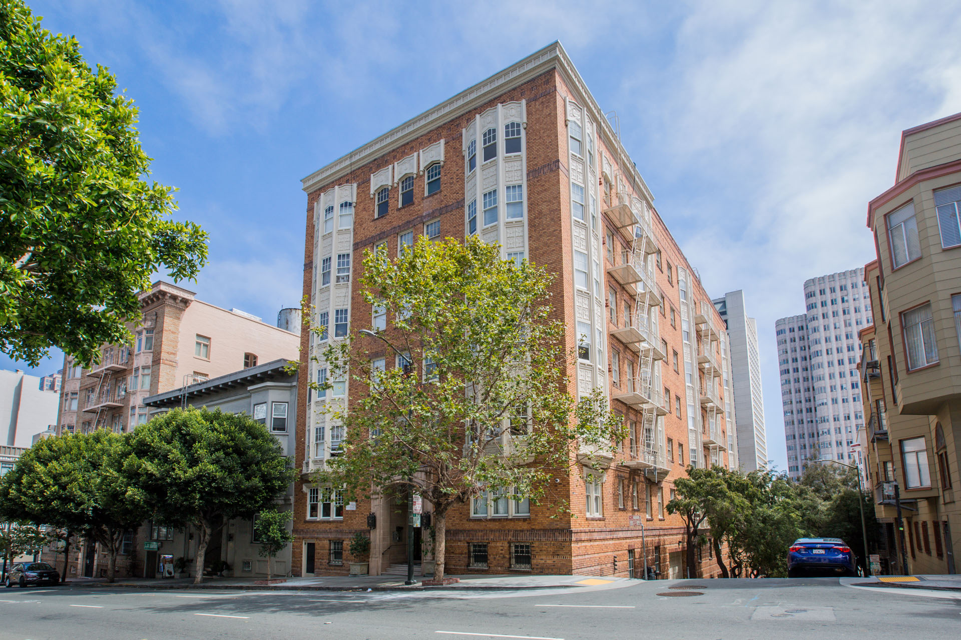 A tall red brick building with a tree in front of it.