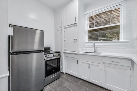 A modern kitchen with a stainless steel refrigerator and white cabinets.