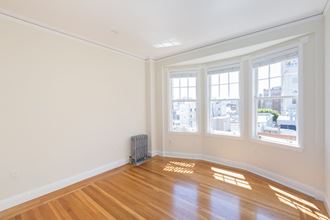 an empty living room with wood floors and three windows