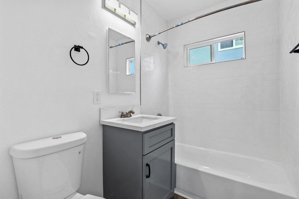 a bathroom with a toilet sink and tub and a mirror