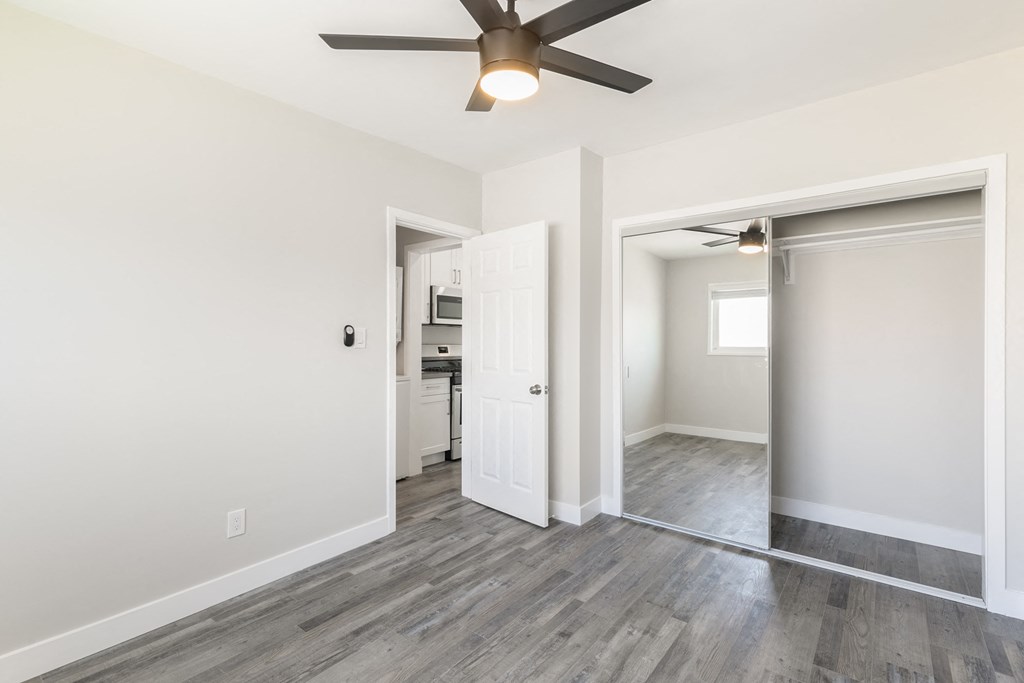 a living room with a ceiling fan and a door to a kitchen